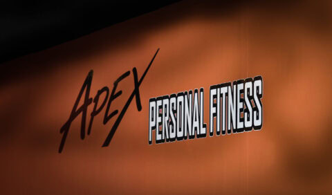 Bright, bold text on a wall showing "Apex Personal Fitness" for fitness and personal trainer branding.