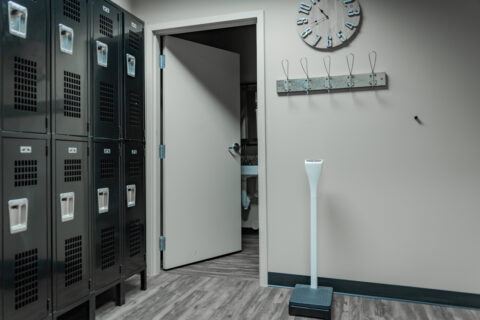 Locker room with lockers, coat hooks, and a digital scale at Apex Personal Fitness center.