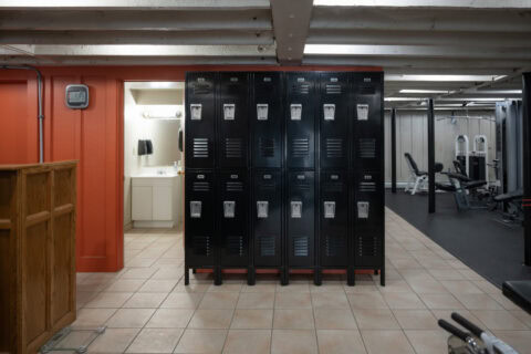 Member lockers with gym floor and weight equipment in background at Apex Personal Fitness Youngstown NY